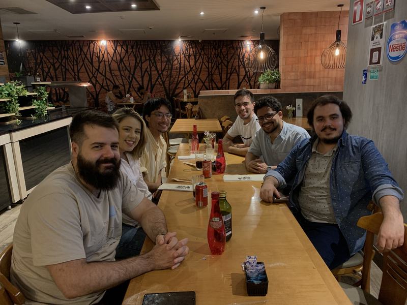 Seis pessoas sorrindo em volta de uma mesa de restaurante
